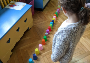 Dziewczynka układa kolorowe kubeczki według podanego rytmu